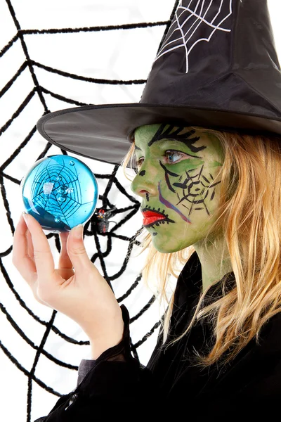 Grüne Halloween-Hexe Mädchen in Großaufnahme hält großen blauen Marmor — Stockfoto