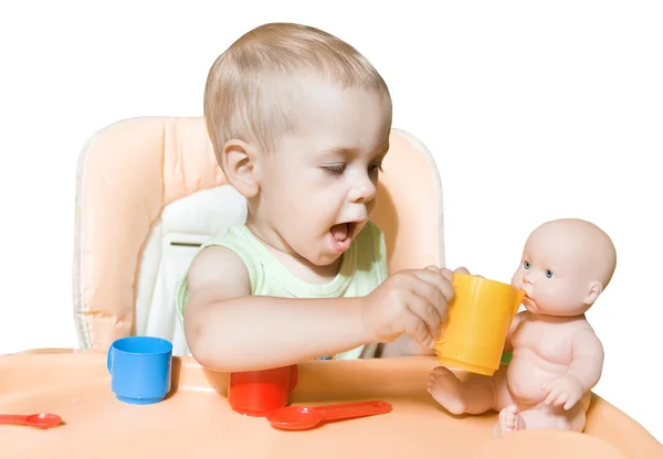 Очаровательный ребенок самостоятельно кормит куклу сидя перед й — стоковое фото