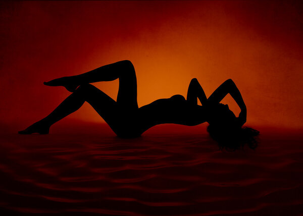 Naked sexy woman silhouette lying at red orange background