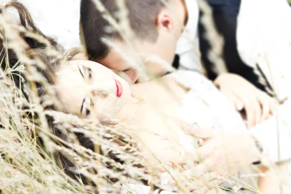 Pareja de bodas. Novia y novio acostado en la hierba y besándose —  Fotos de Stock