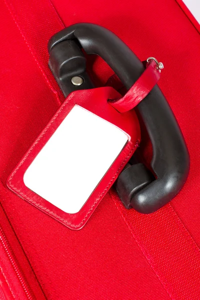 Red suitcase with blank identification tag over white. Closeup. — Stock Photo, Image
