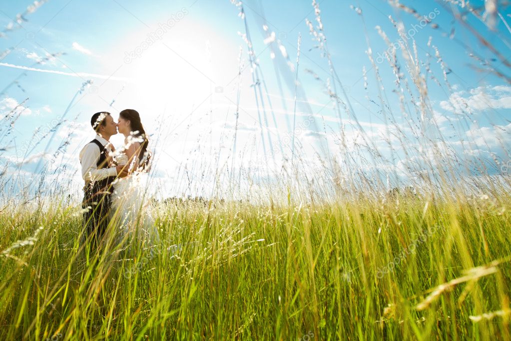 Kissing bride and groom in sunny grass