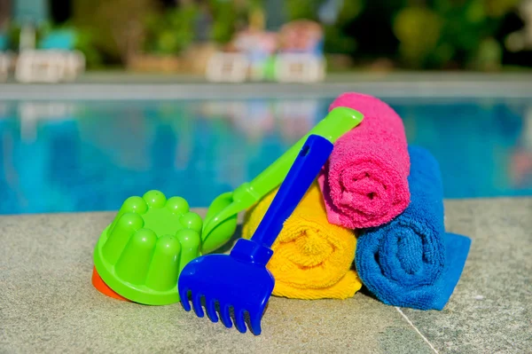 Zabawki i walcowane ręczniki przy basenie — Zdjęcie stockowe