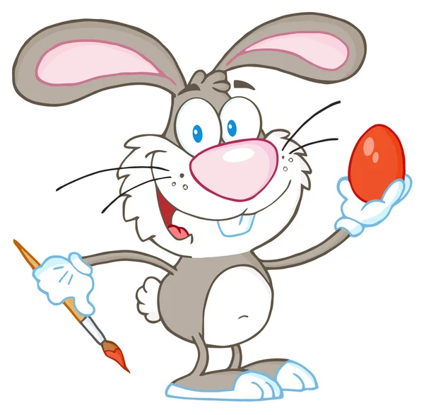 Серый пасхальный кролик рисует яйцо — стоковое фото