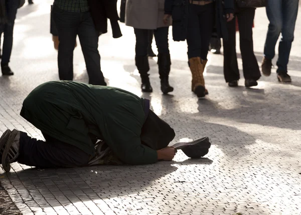 Beggar kneeling on a pavement — Stock Photo, Image