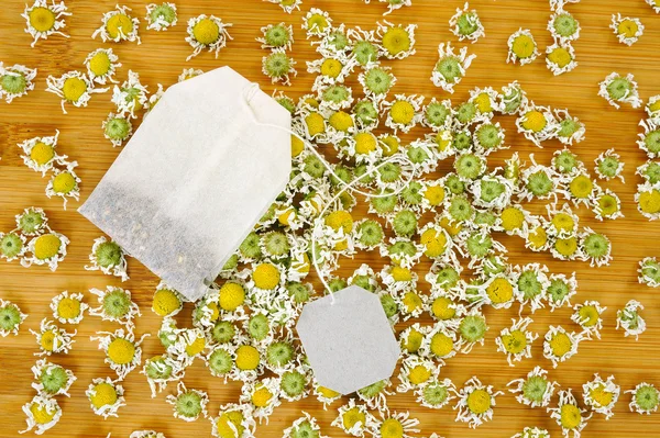 Beutel Kamillentee mit trockenen Kamillenblüten über Holzgrund — Stockfoto