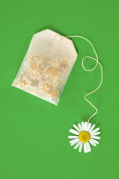 Bag of chamomile tea over green background - concept — Stock Photo, Image