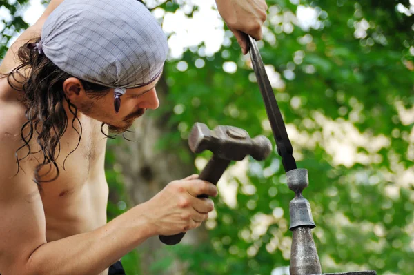 Joven herrero martillando hierro caliente en yunque —  Fotos de Stock
