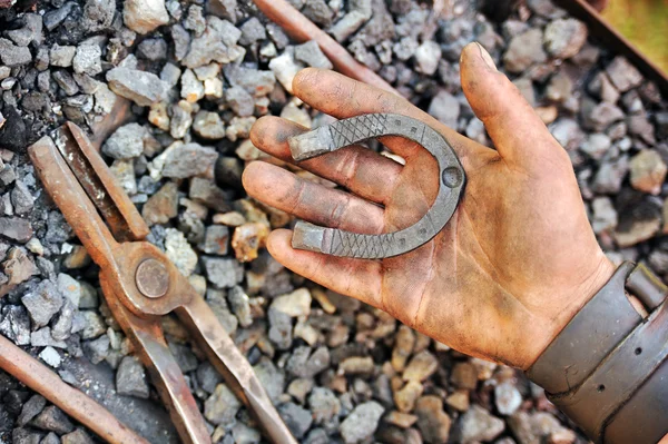 Detalhe da mão suja segurando ferradura - ferreiro — Fotografia de Stock
