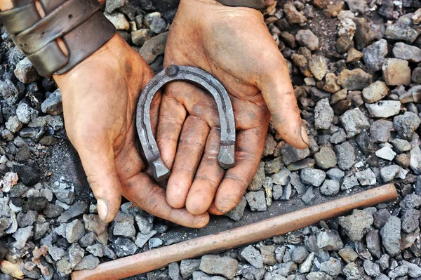 Detail of dirty hands holding horseshoe - blacksmith — Stock Photo, Image
