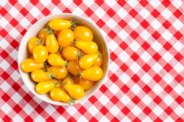 Yellow tomatoes on picnic tablecloth clipart