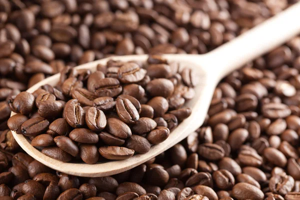 Kávová zrna na dřevěnou lžící — Stock fotografie