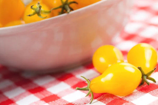 Gele tomaten op picknick tafellaken — Stockfoto