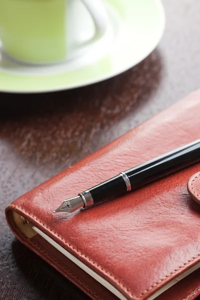 Pen on diary and coffee mug — Stock Photo, Image