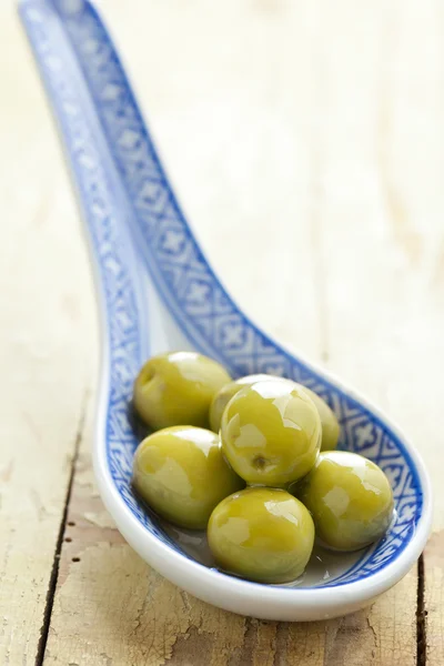 Зеленые оливки в керамической ложке — стоковое фото
