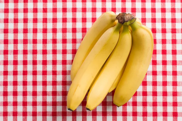Yellow bananas on checkered tablecloth — Stock Photo, Image