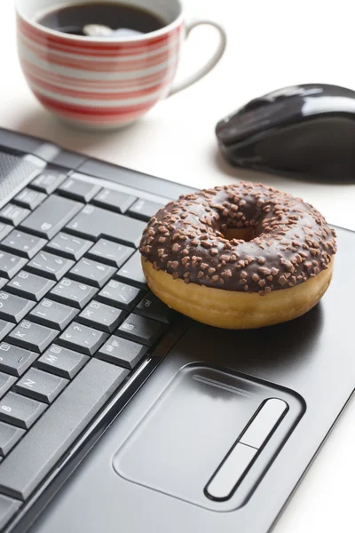 Pause im Büro. Donut auf Laptop-Tastatur — Stockfoto