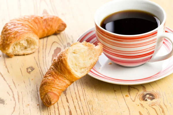 Breaking croissant with coffee — Stock Photo, Image