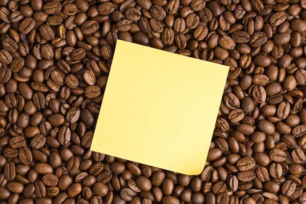 Kahve çekirdekleri zemin üzerine sarı not kağıdı — Stok fotoğraf