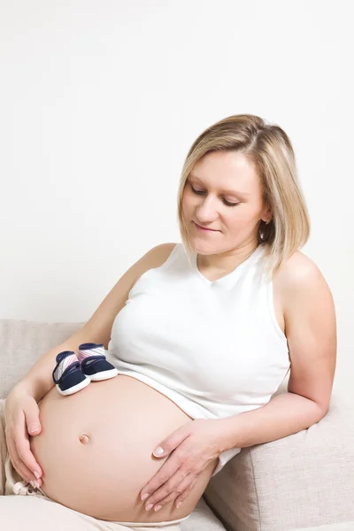 Mujer embarazada sentada en el sofá — Foto de Stock