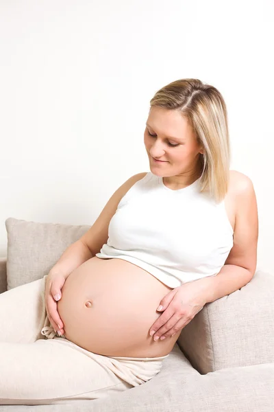 Femme enceinte assise sur le canapé — Photo