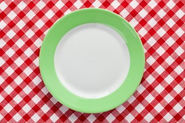 Green plate on checkered tablecloth clipart