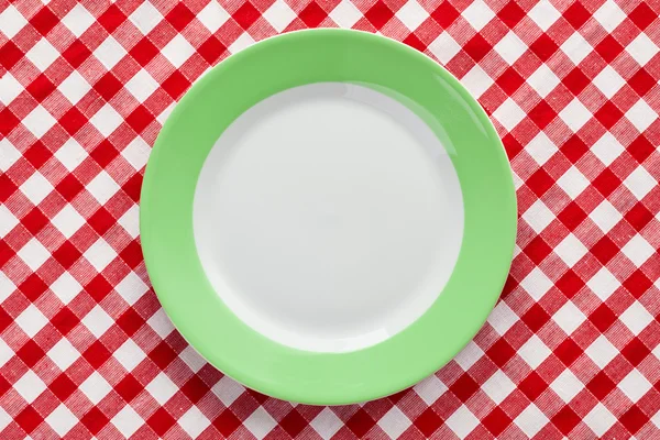 Grüner Teller auf karierter Tischdecke — Stockfoto
