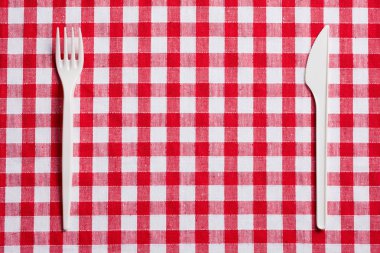 Plastic cutlery on checkered tablecloth clipart