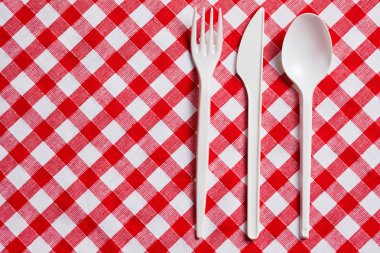 Plastic cutlery on checkered tablecloth clipart