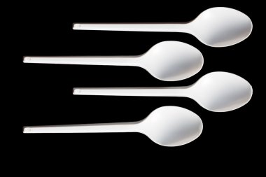 Plastic spoons on black background clipart