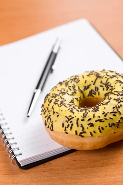 Sweet doughnut and spiral notebook — Stock Photo, Image