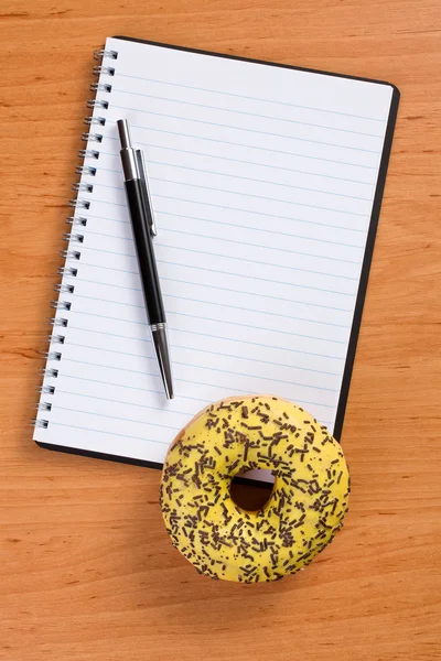 Doce donut e caderno em espiral — Fotografia de Stock