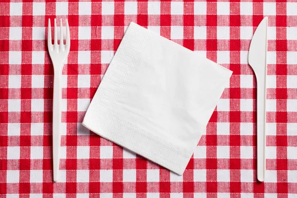 Talheres de plástico na toalha de mesa quadriculada — Fotografia de Stock