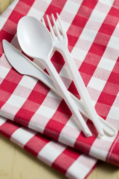 Plastic cutlery on checkered tablecloth — Stock Photo, Image