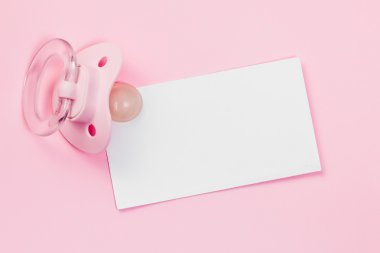 Pacifier and blank card on pink background clipart