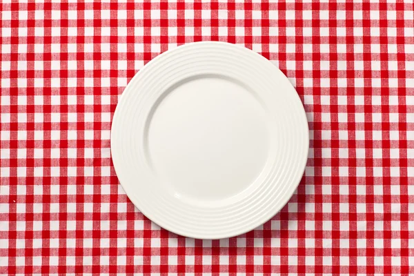 White plate on checkered tablecloth — Stock Photo, Image