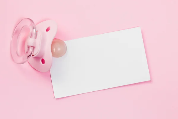 Schnuller und leere Karte auf rosa Hintergrund — Stockfoto