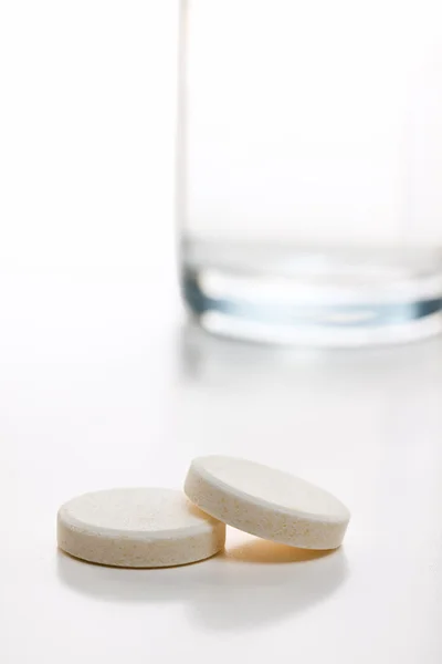 Сияющие таблетки и стекло с водой — стоковое фото