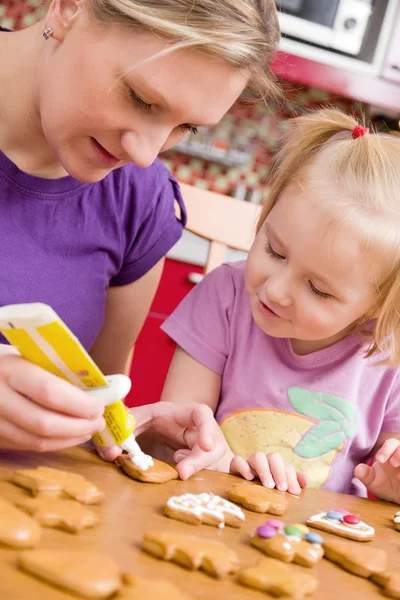 Mother and her daughter decorate ginger bread — Stock Photo, Image