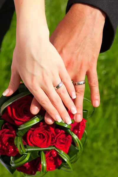 Mani con anelli sul bouquet da sposa — Foto Stock