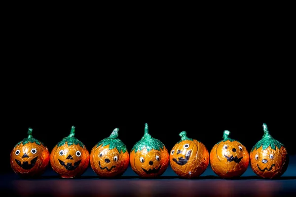 Orange pumpkin wrapped chocolates in a row — Stock Photo, Image