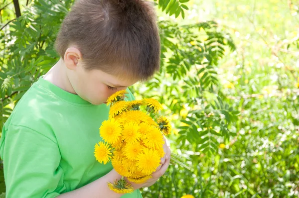 Un garçon avec un bouquet de pissenlits dans le parc — Photo