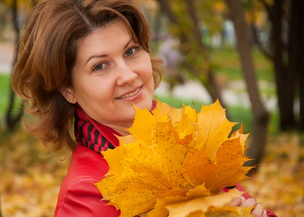 Женщина в осеннем парке с букетом кленовых листьев — стоковое фото