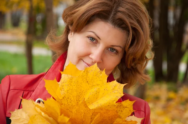 Woman in autumn park with a bouquet of maple leaves — Stock Photo, Image
