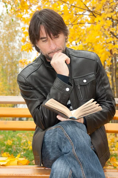 Hombre de mediana edad con un libro en el parque de otoño —  Fotos de Stock