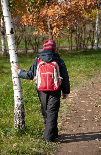 Um menino com uma mochila no outono City Park — Fotografia de Stock