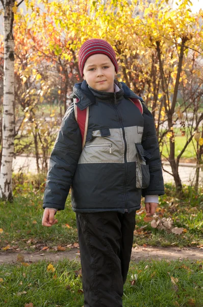 Ein Junge mit Rucksack im herbstlichen Stadtpark — Stockfoto