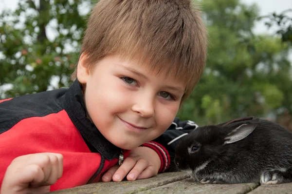 stock image A boy with a rabbit in the garden on a summer residence