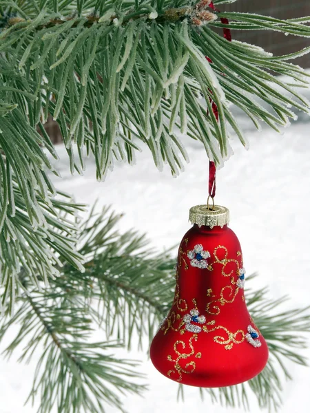 Een mooie rode kerstversiering op een besneeuwde kerstboom — Stockfoto