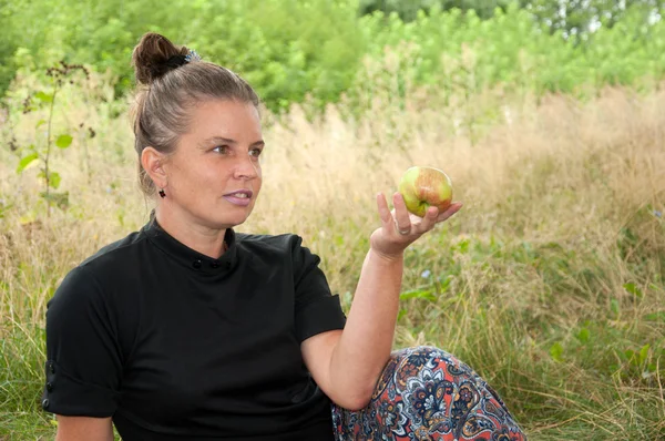 Μέσης ηλικίας γυναίκα με ένα μήλο στο χέρι του — Φωτογραφία Αρχείου
